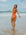 AFL player Shelby frolicking in the water at the beach, wearing the JAYD Airlie cross-back one piece swimsuit in Blaze red on the beach.