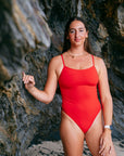Ski paddler Jenaya Massie leaning against a rock at the beach wearing the JAYD Swimwear Airlie one piece 