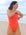 Open water swimmer Madi wearing the Albi one piece in Blaze red, standing on a beach gazing into the distance.
