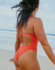 JAYD models Madi spinning around on a beach wearing the flattering Albi one piece swimsuit in vibrant Blaze red.