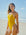 AFLW player Shelby standing on a beach wearing the JAYD Albi one piece in Ignite yellow.