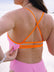Close-up back view of the Airlie one piece triple back strap in flare orange, contrasting against the fairy floss pink swimsuit body.