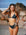 JAYD model Cass walking on a beach listening to a vintage music player, wearing the Kiama bikini top in Carbon grey with matching Carbon bottoms.