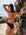 JAYD Swimwear model leaning against a rock at the beach, shading her eyes from the sun, wearing the Tallow one piece in sangria.