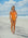 Triathlete Charlotte standing on a beach wearing the JAYD Swimwear Zimmy one piece in Flare orange.