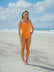 Triathlete Charlotte standing on a beach wearing the JAYD Swimwear Zimmy one piece in Flare orange.