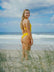 Surf Life Saving athlete Brodee standing on a grassy beach wearing the JAYD Zimmy one piece in Ignite yellow.